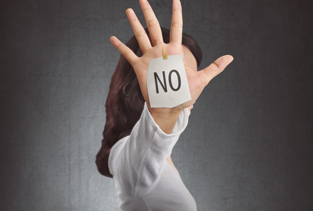 Person holding up hand with sign on it saying 'no'