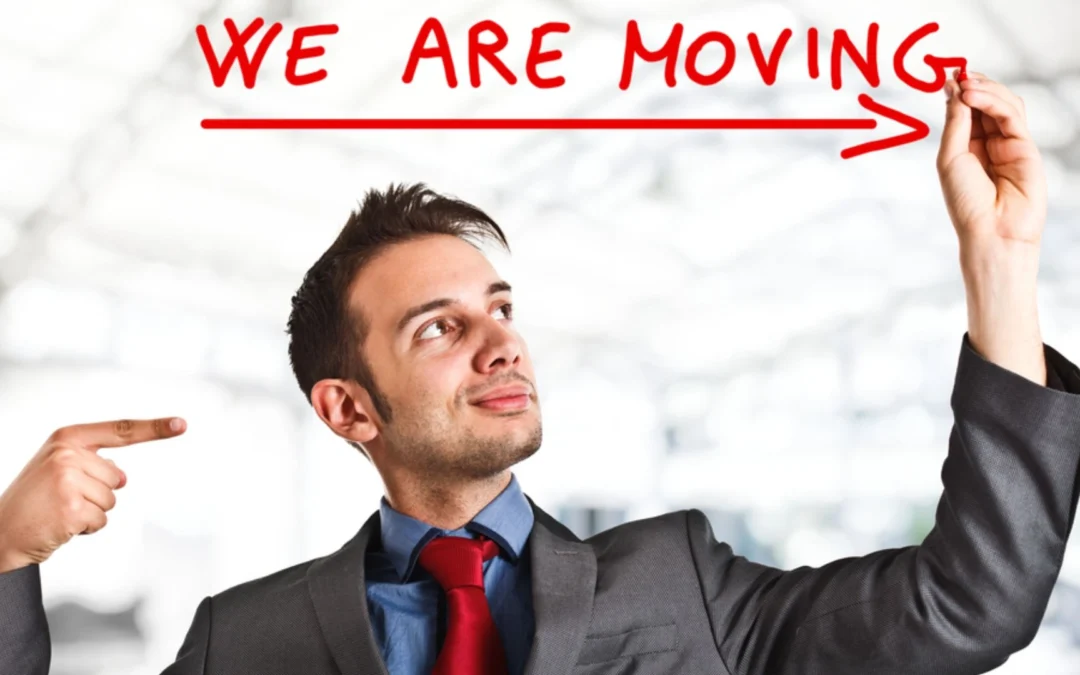 man writing 'we are moving' on a piece of glass