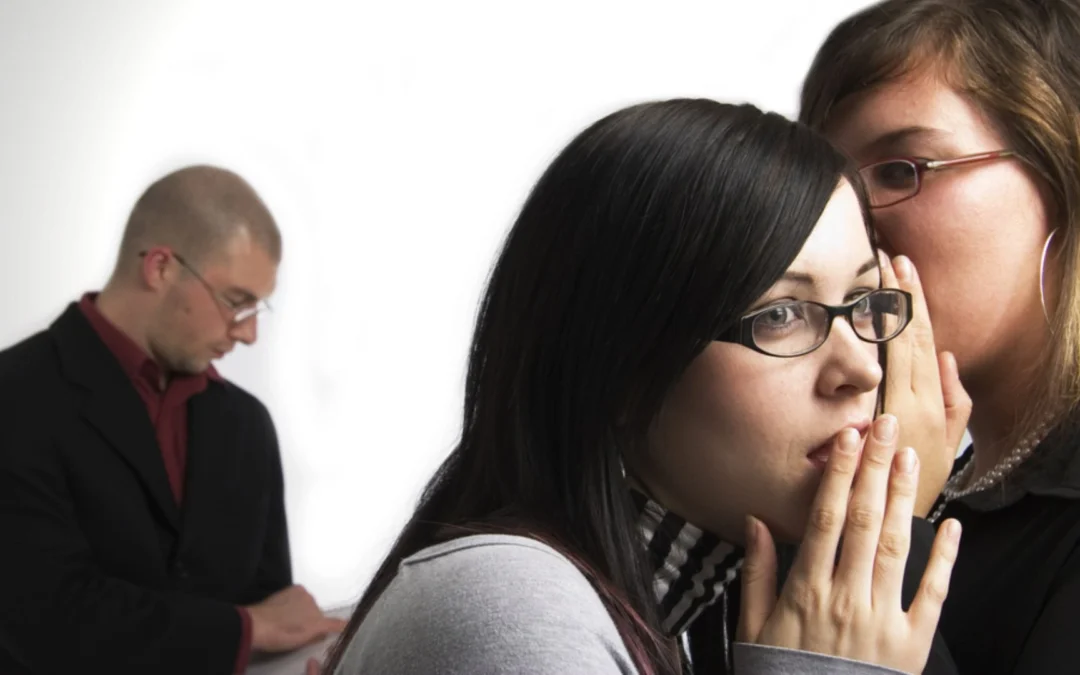 person whispering in a colleague's ear