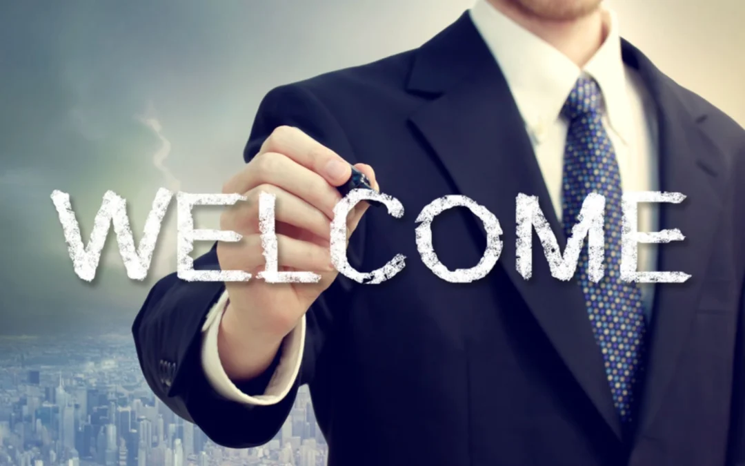 person writing 'welcome' on a piece of glass