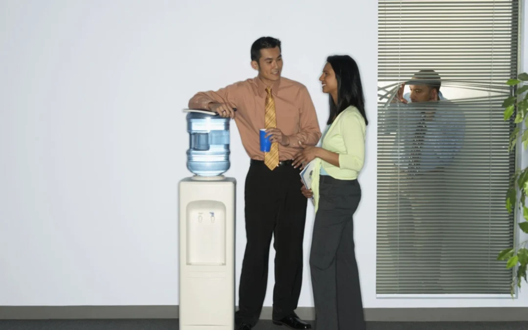 two colleagues talking by a water cooler
