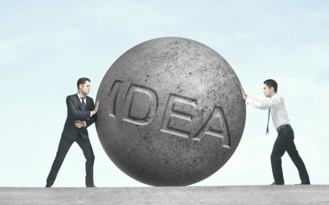 two people pushing a stone with the word 'idea' written on it