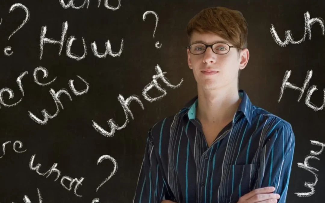 person standing in front of a blackboard with 'who, what, when, where, how' written all over it