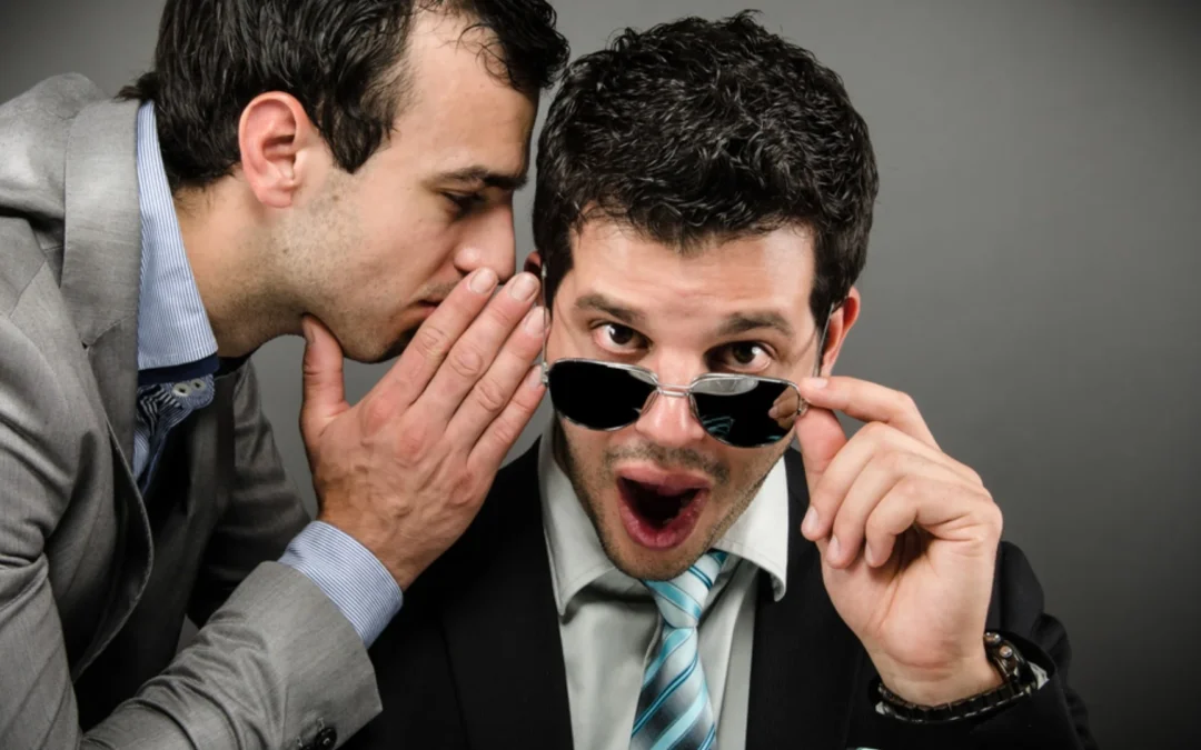 person whispering into another's ear