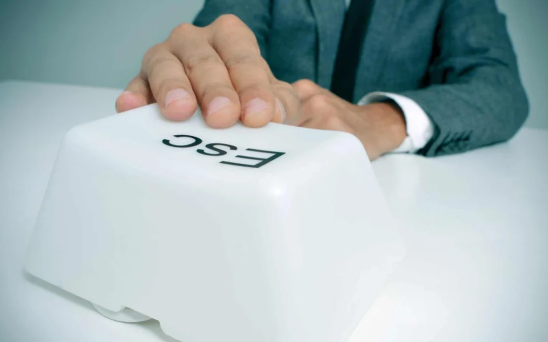 person pushing a large 'escape' button