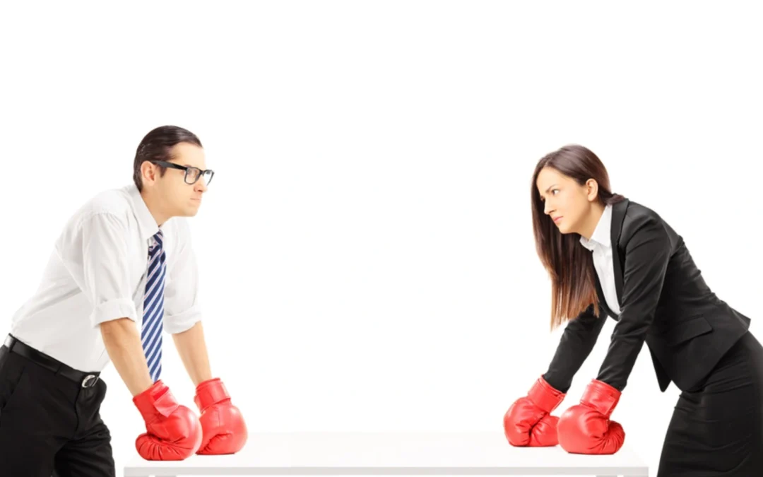 two business people facing each other, wearing boxing gloves