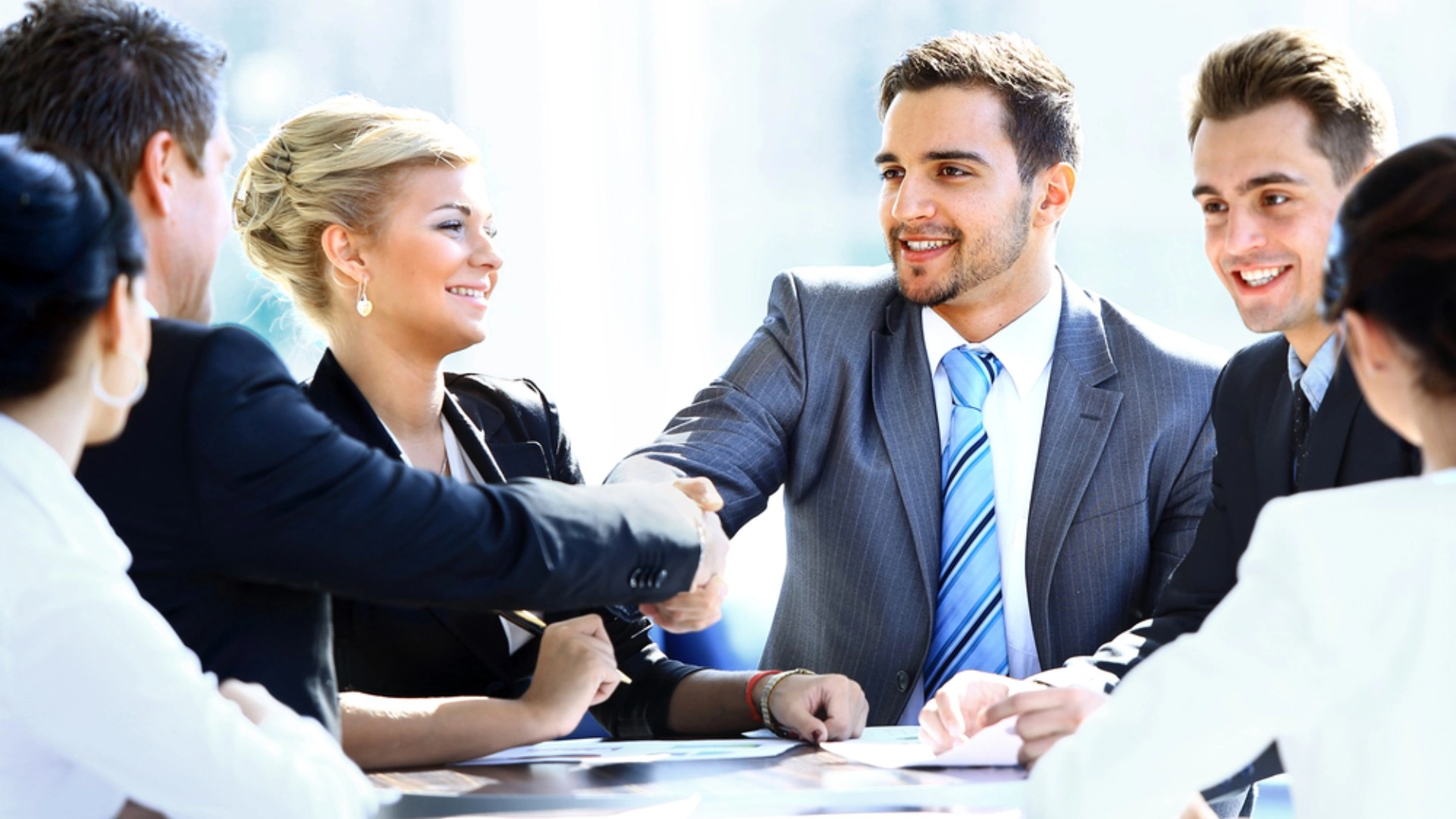 people shaking hands across a meeting table