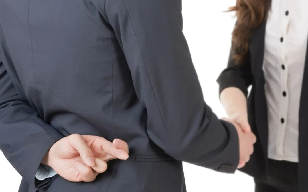 person shaking hands with a teammate while their fingers are crossed behind their back