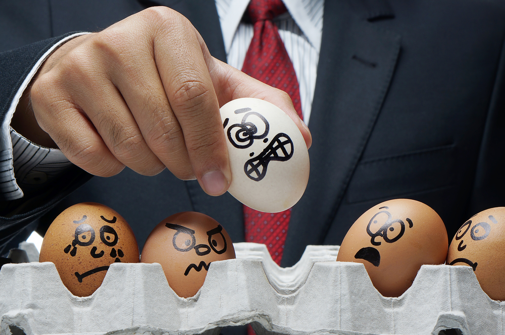boss holding up eggs painted with scared expressions