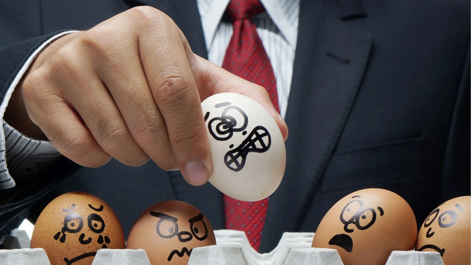 boss holding up eggs painted with scared expressions