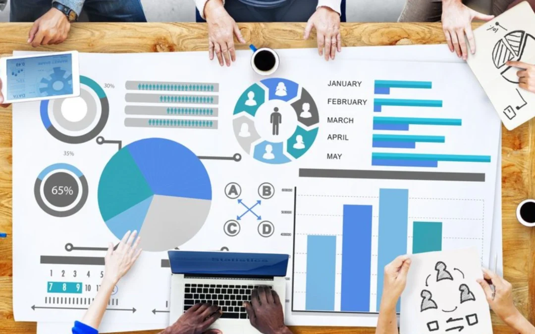 group of teammates sitting around a piece of paper with charts and graphs on it