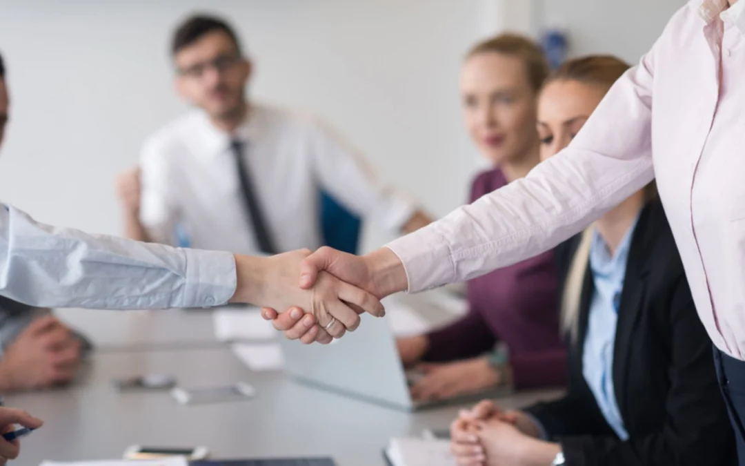 Two people shaking hands at a team meeting