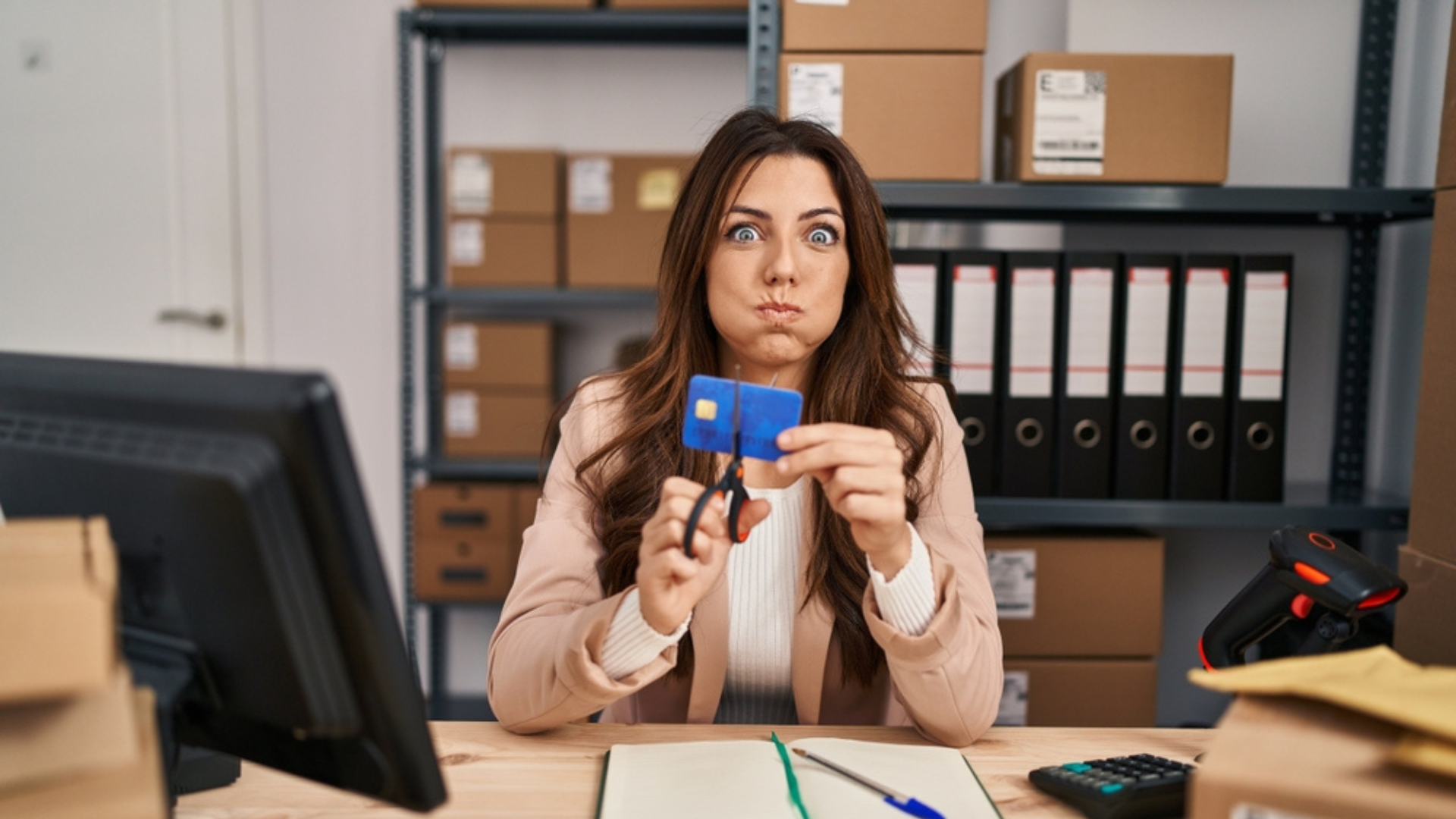 Woman sitting at her desk cutting up a credit card.