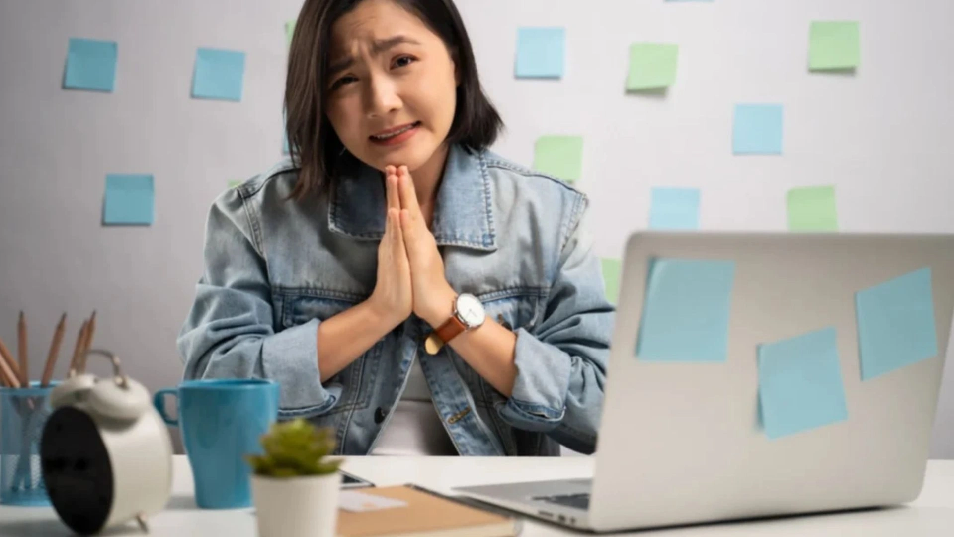Woman working from home, hands together asking for foregiveness