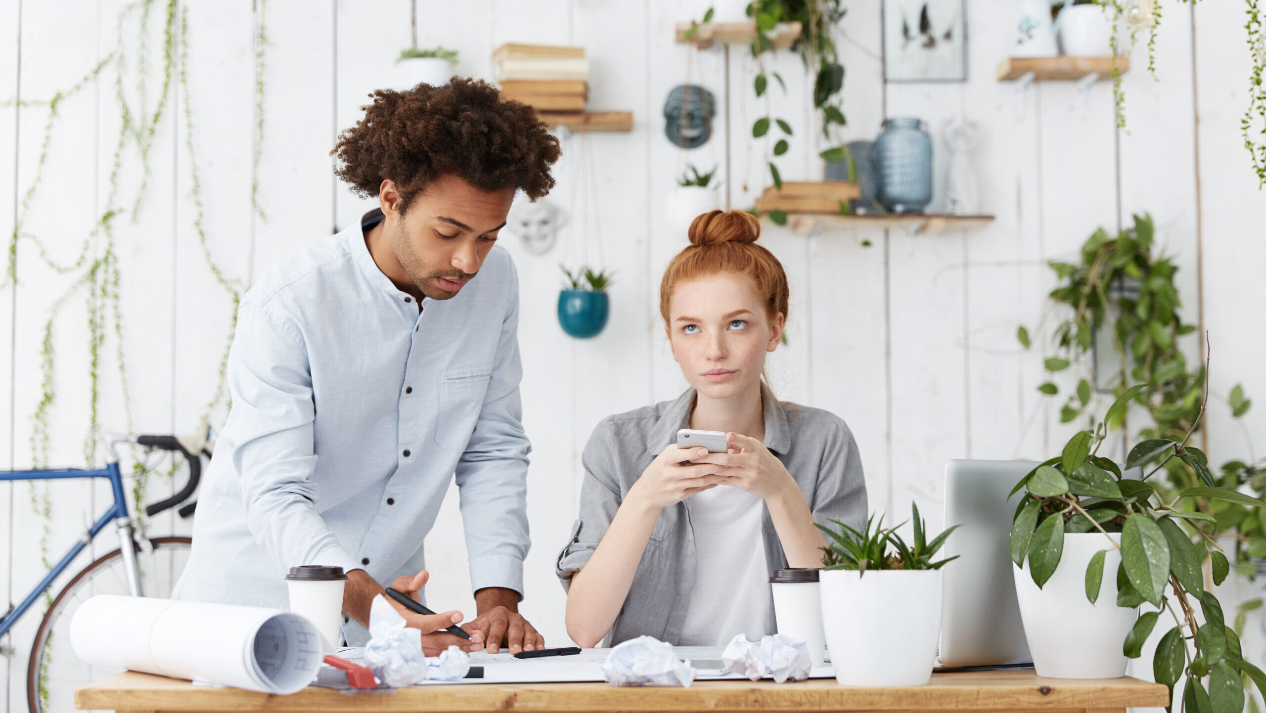 Man leaning over woman's desk talking while she's not listening