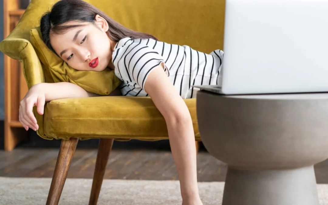 Woman lying face down on couch looking at her computer