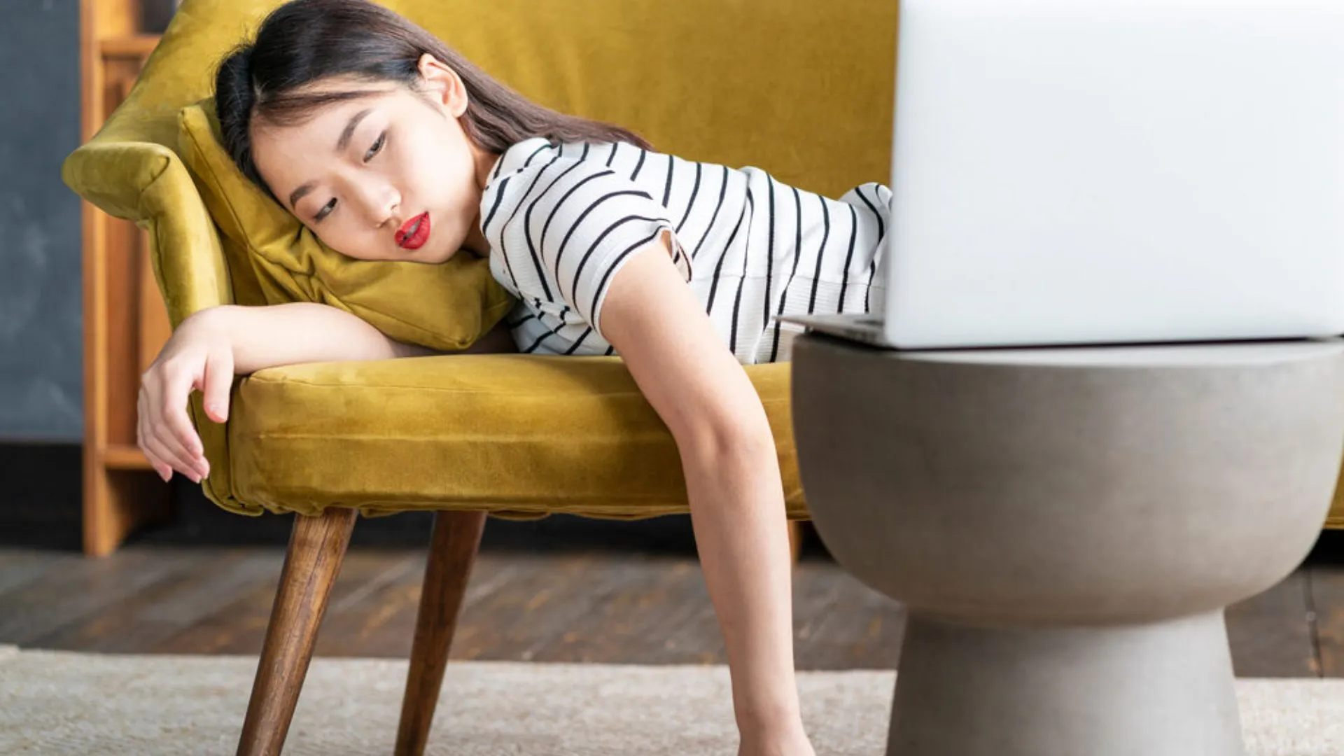 Woman lying face down on couch looking at her computer
