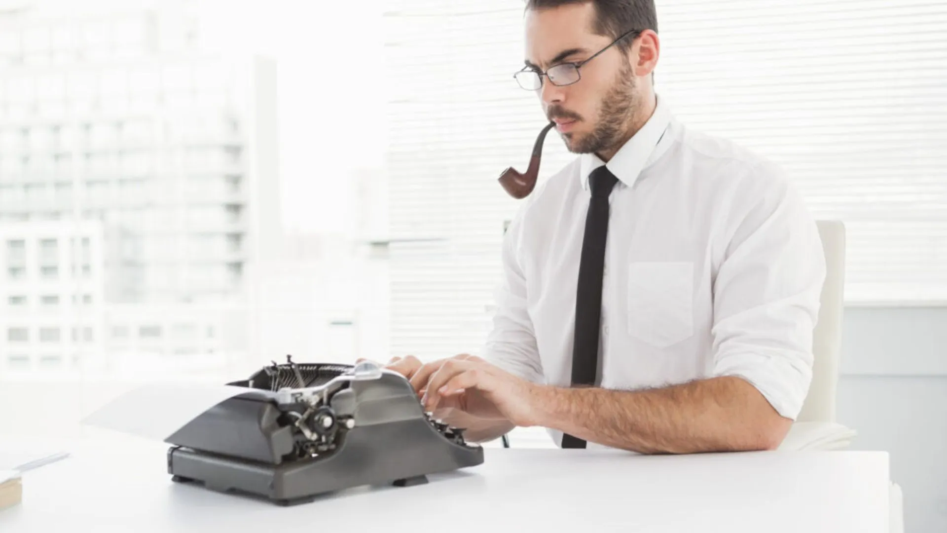 Young professional typing and smoking a pipe