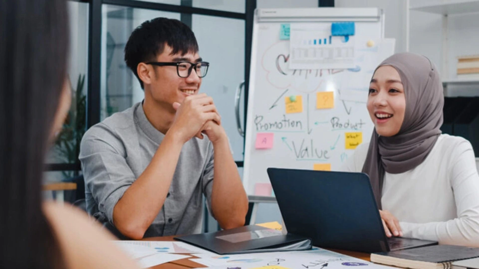 Team working around a table in an office. Smiling.