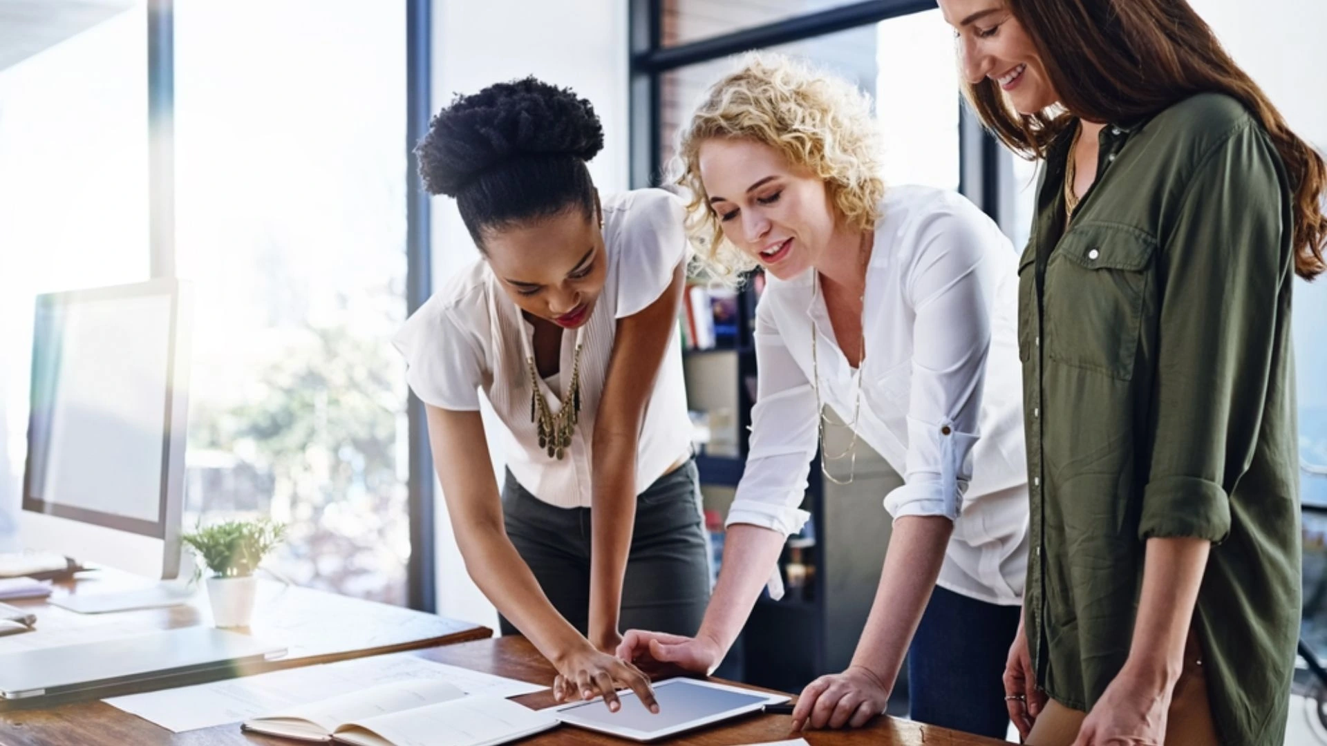 Three people standing over a table discussing an issue