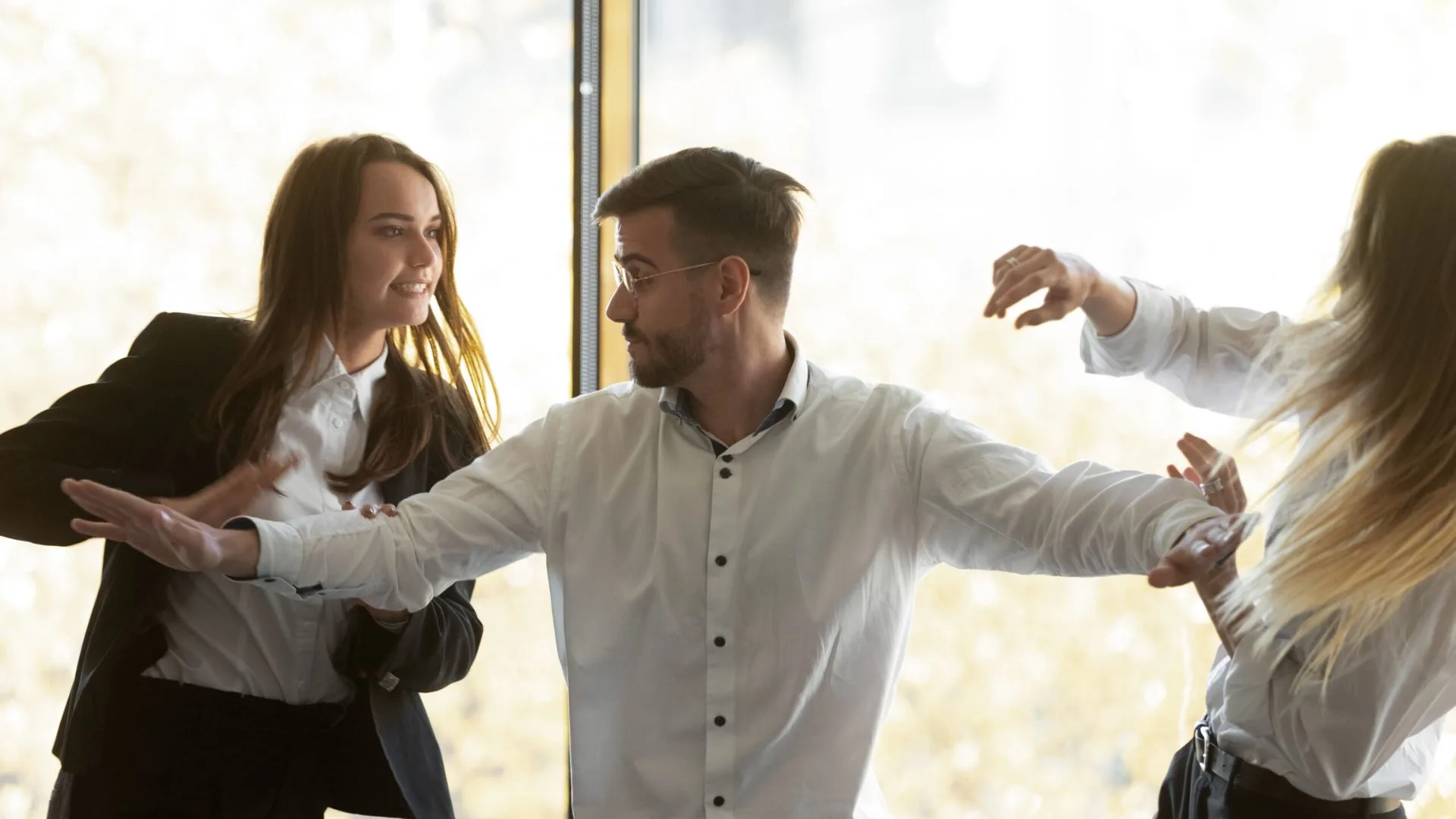 Man standing in between to women fighting