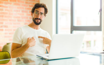 Man at desk pointing to himself as if to say 