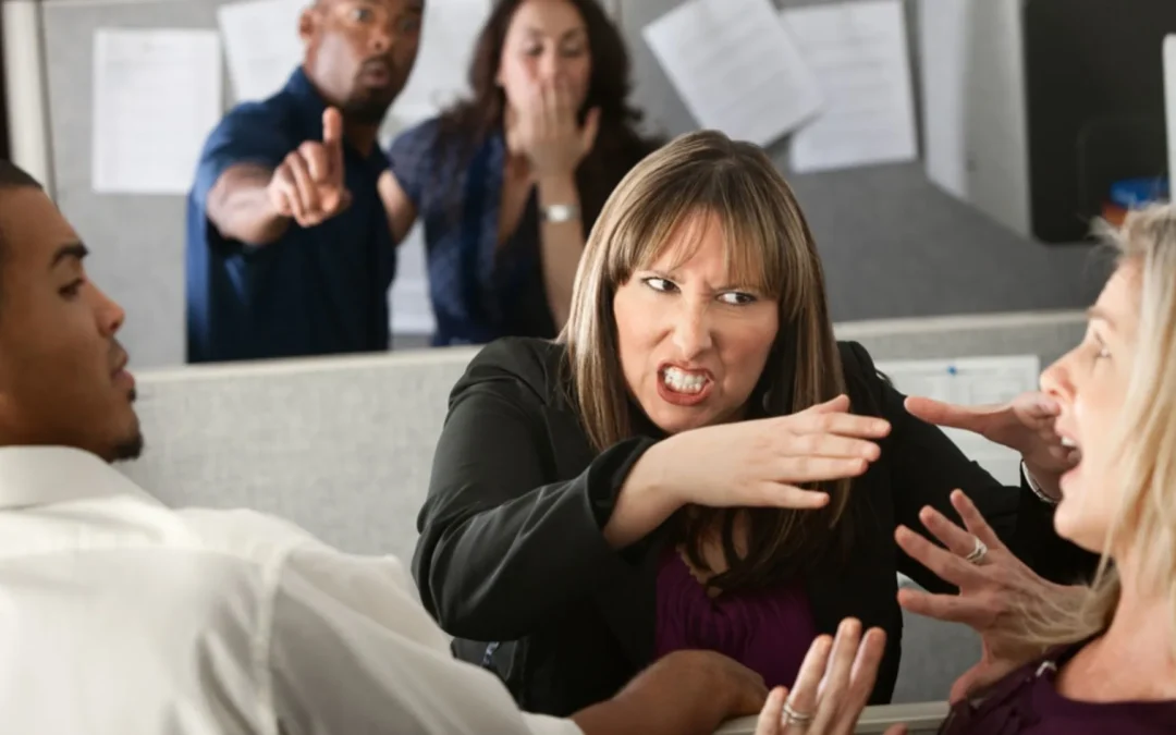 Angry woman leaning over her desk pretending to strangle a teammate while others watch