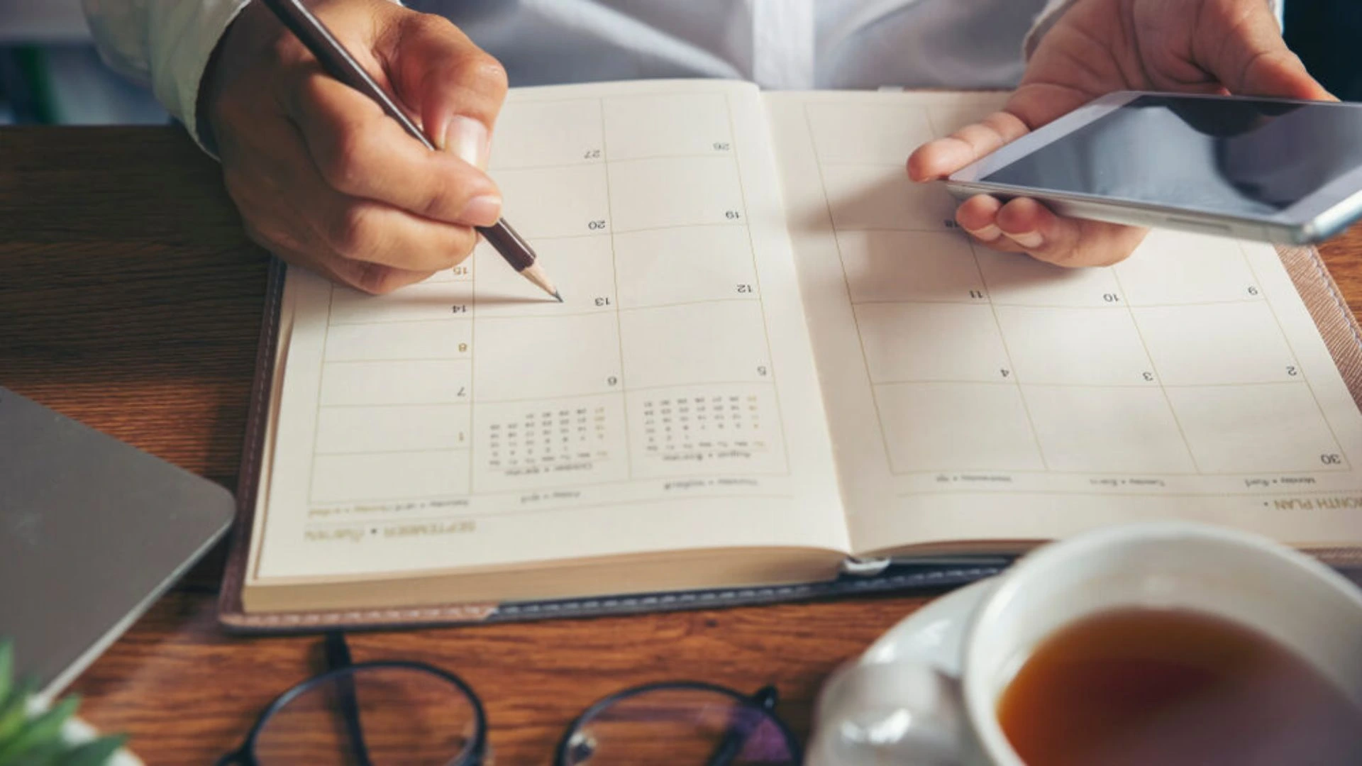 Person writing a schedule in their calendar to structure your time