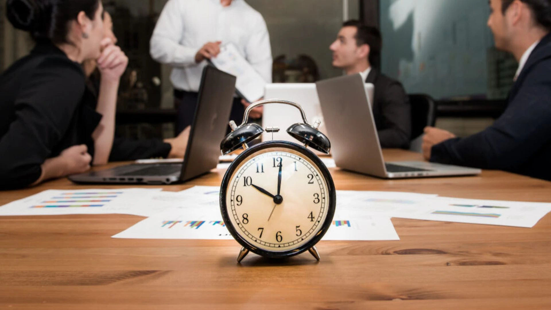 Team meeting with a clock on the table to make their meeting shorter