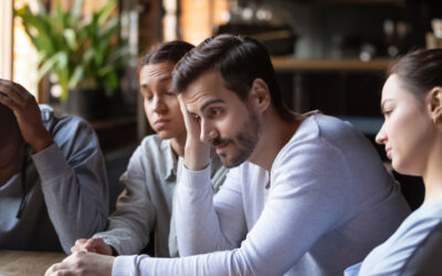 Team sitting around a table looking really down.