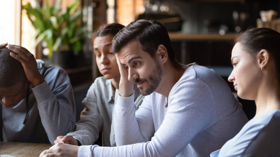 Team sitting around a table looking really down.