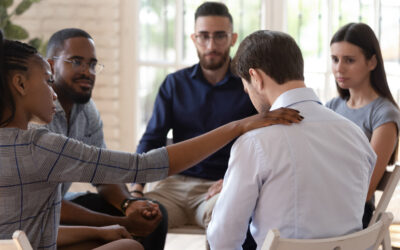 Person reaching out to put a hand on a shoulder of a colleague feeling sad.