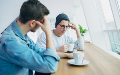 Two colleagues sitting having coffee. One colleague looks sad.