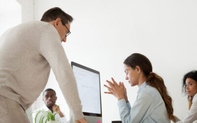 Manager standing over a team member who looks upset and spreading emotional contagion