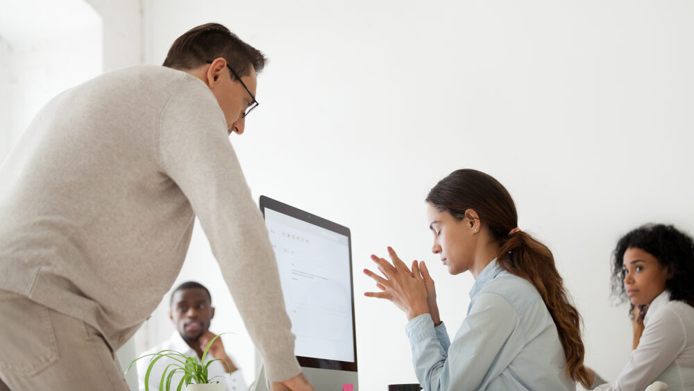 Manager standing over a team member who looks upset and spreading emotional contagion