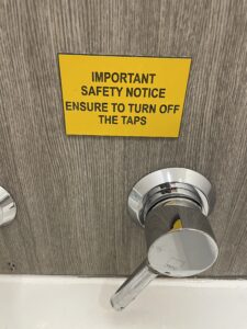 Sign on a bathroom wall that says, "Important safety notice. Ensure to turn o the taps." 