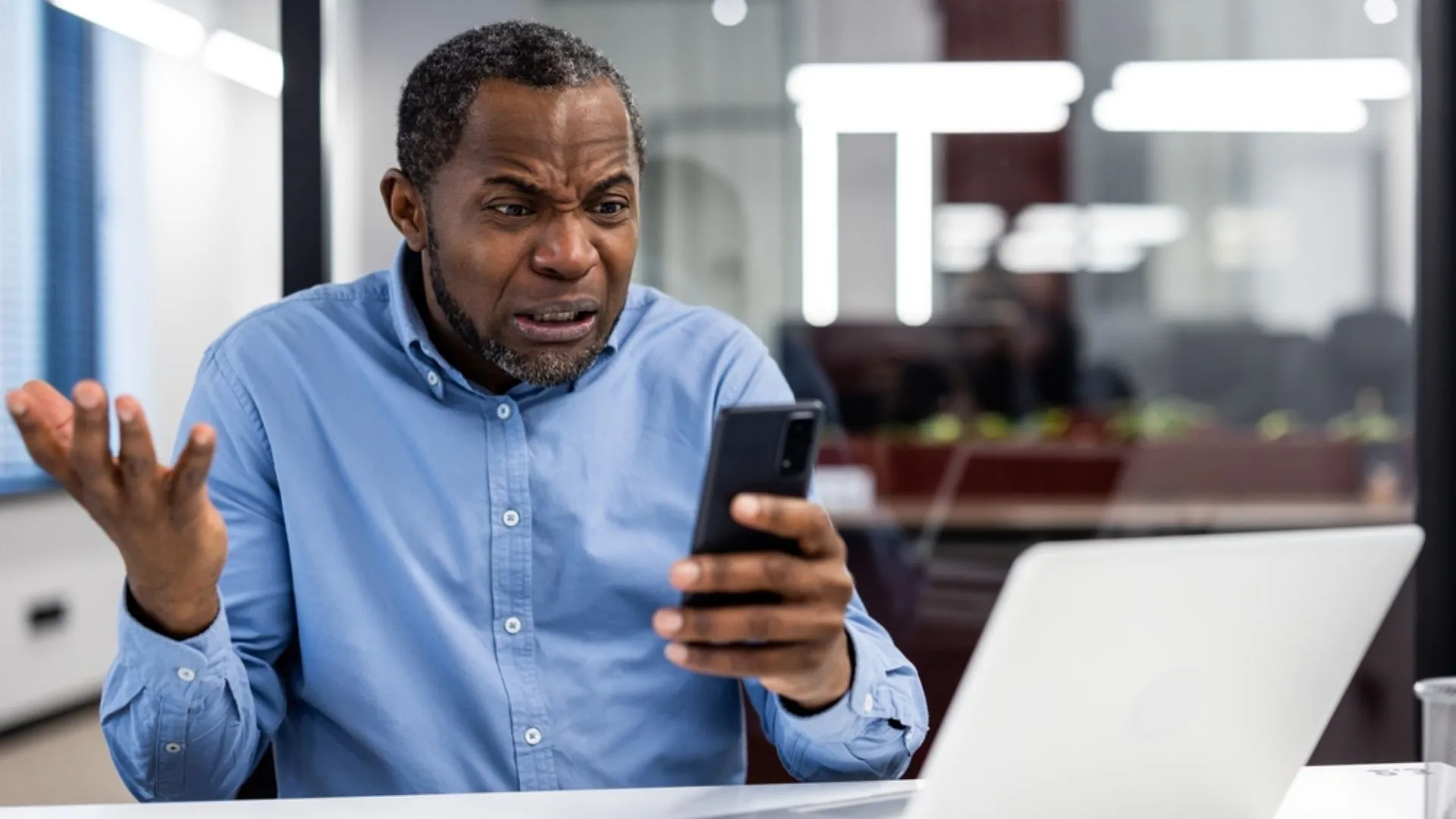 Black man looking at his phone frustrated with what he's reading.