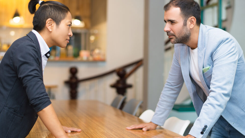 Two colleagues staring each other down across the table.