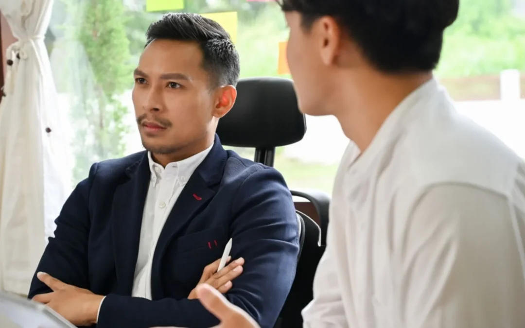 Two colleagues one with arms crossed acting passive-aggressively