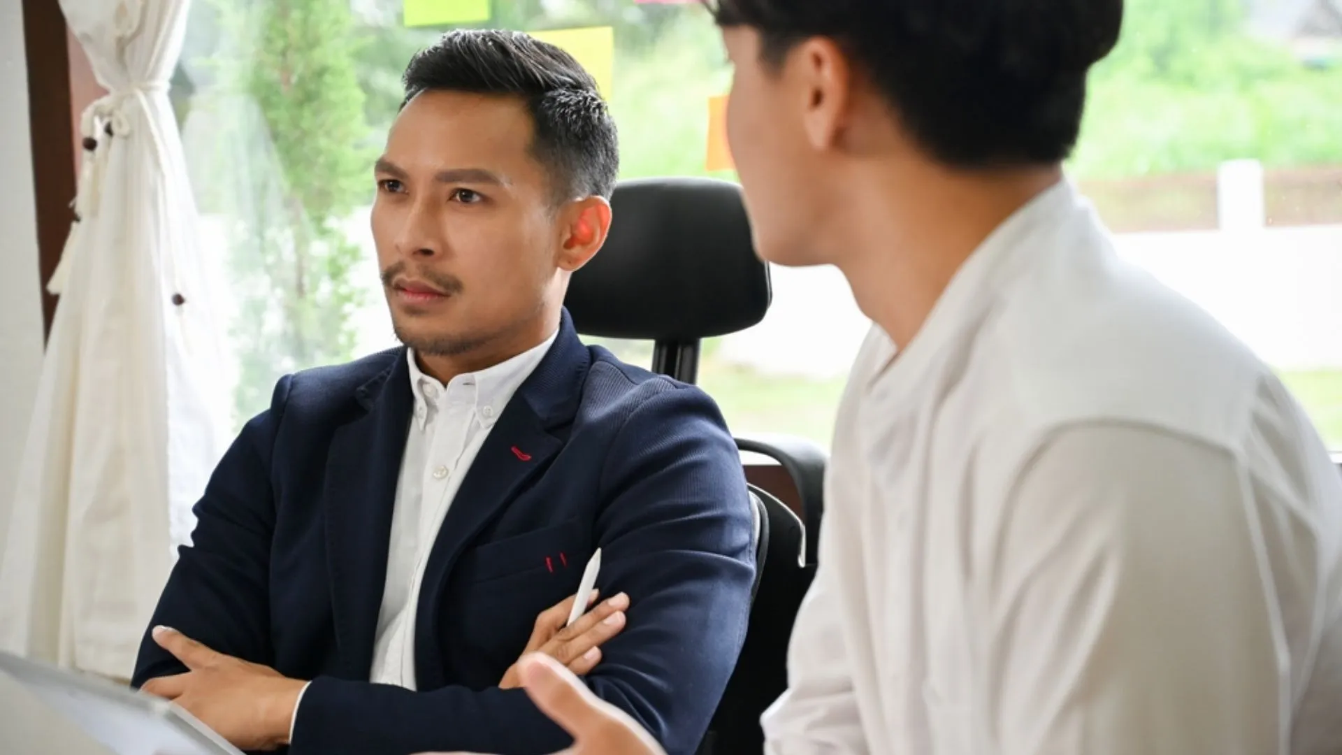 Two colleagues one with arms crossed acting passive-aggressively