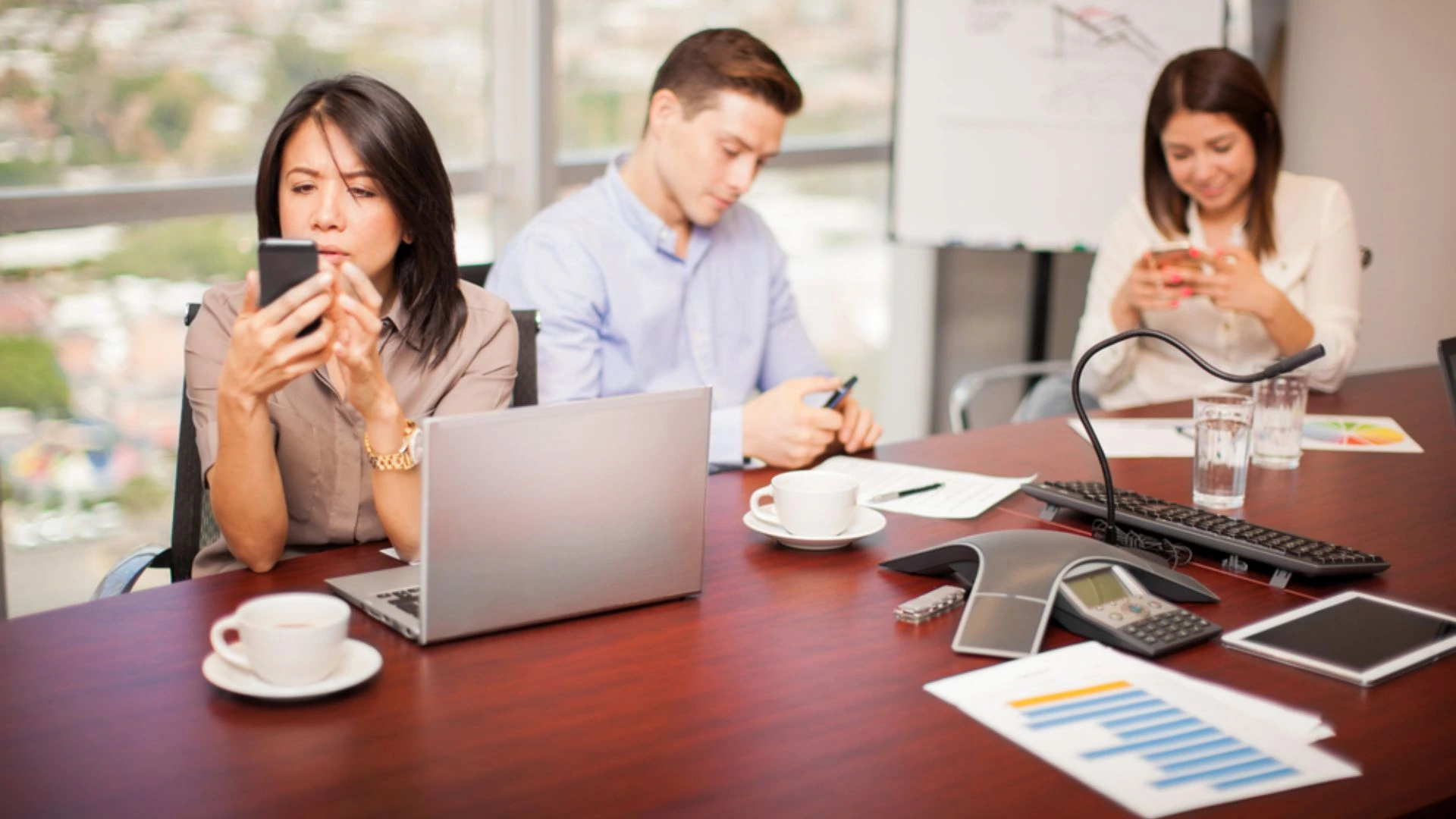 Team meeting where people are multitasking on their phones