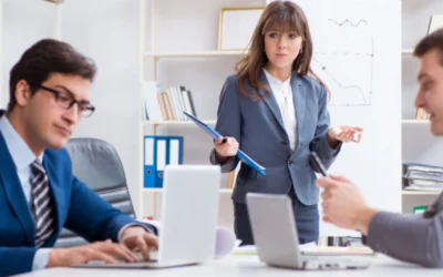 Male employee working at the computer ignoring a woman who looks frustrated