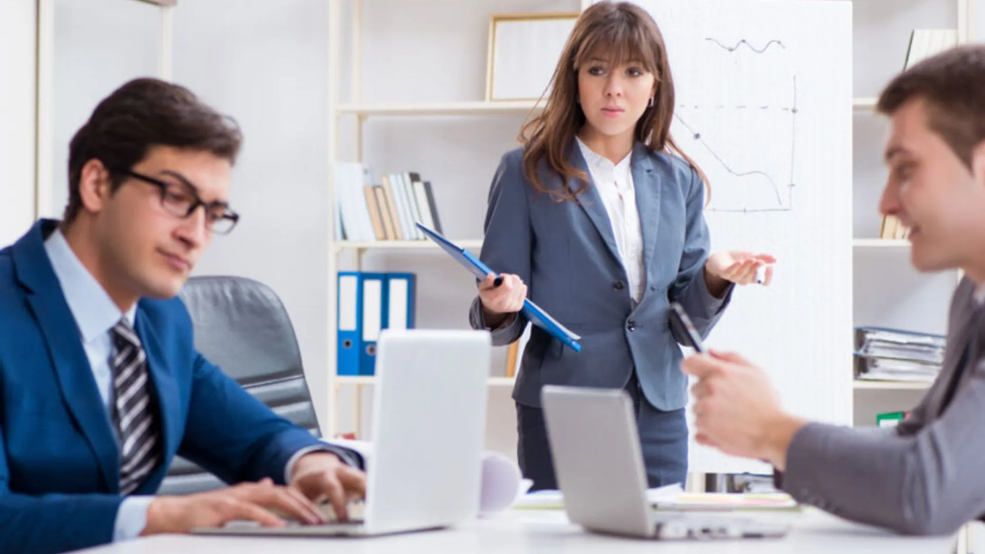 Male employee working at the computer ignoring a woman who looks frustrated