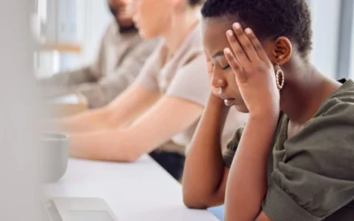 Person with her head in her hands sitting at the computer suffering from job stress
