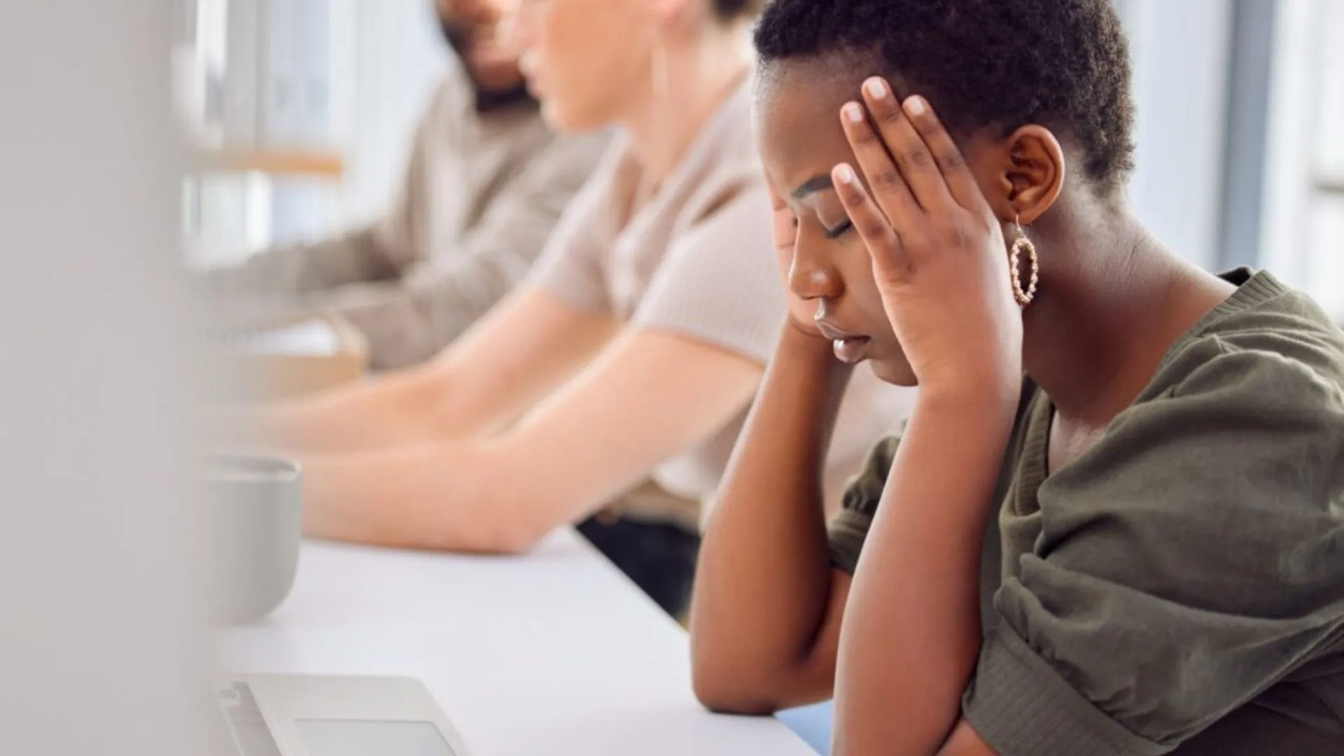 Person with her head in her hands sitting at the computer suffering from job stress