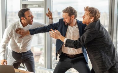 A man in between two colleagues holding them off as they try to fight each other.